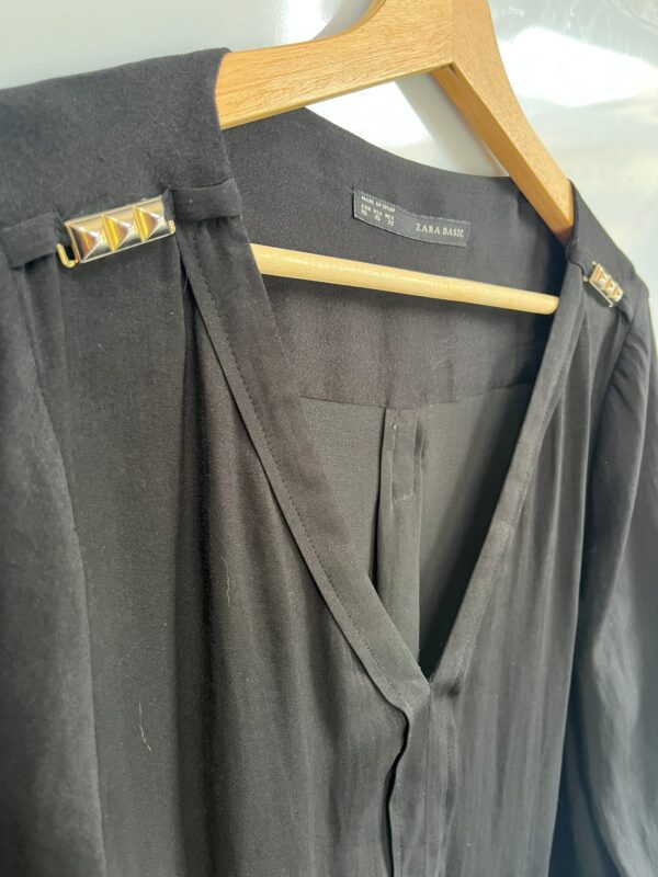 Blusa negra fluida con detalles metálicos